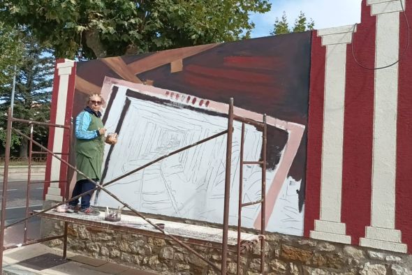 Irene Lario pinta el mural ‘Bocamina’ en la pared  de una finca en Escucha