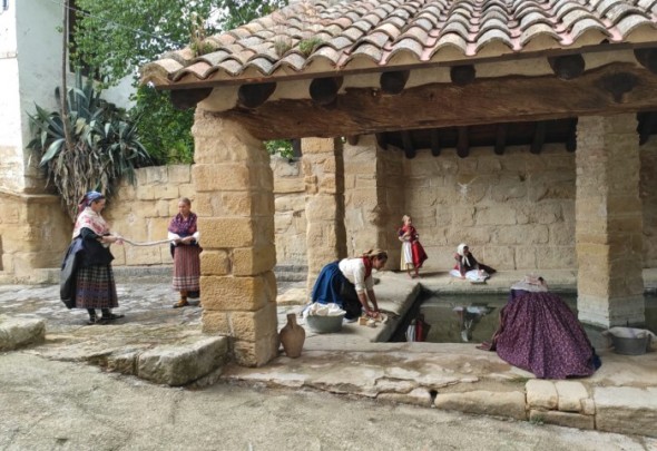 Varias mujeres y niñas limpiando la ropa con jabón de tajo en el lavadero de Castelserás, escenario de una de las fotografías que componen el almanaque. Dabí Latas