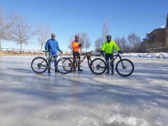 Varios ciclistas, sobre la laguna del Campillo helada