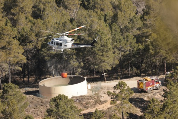 Un helicóptero de extinción de incendios carga agua para tratar de apagar los focos activos en el entorno de San Agustín